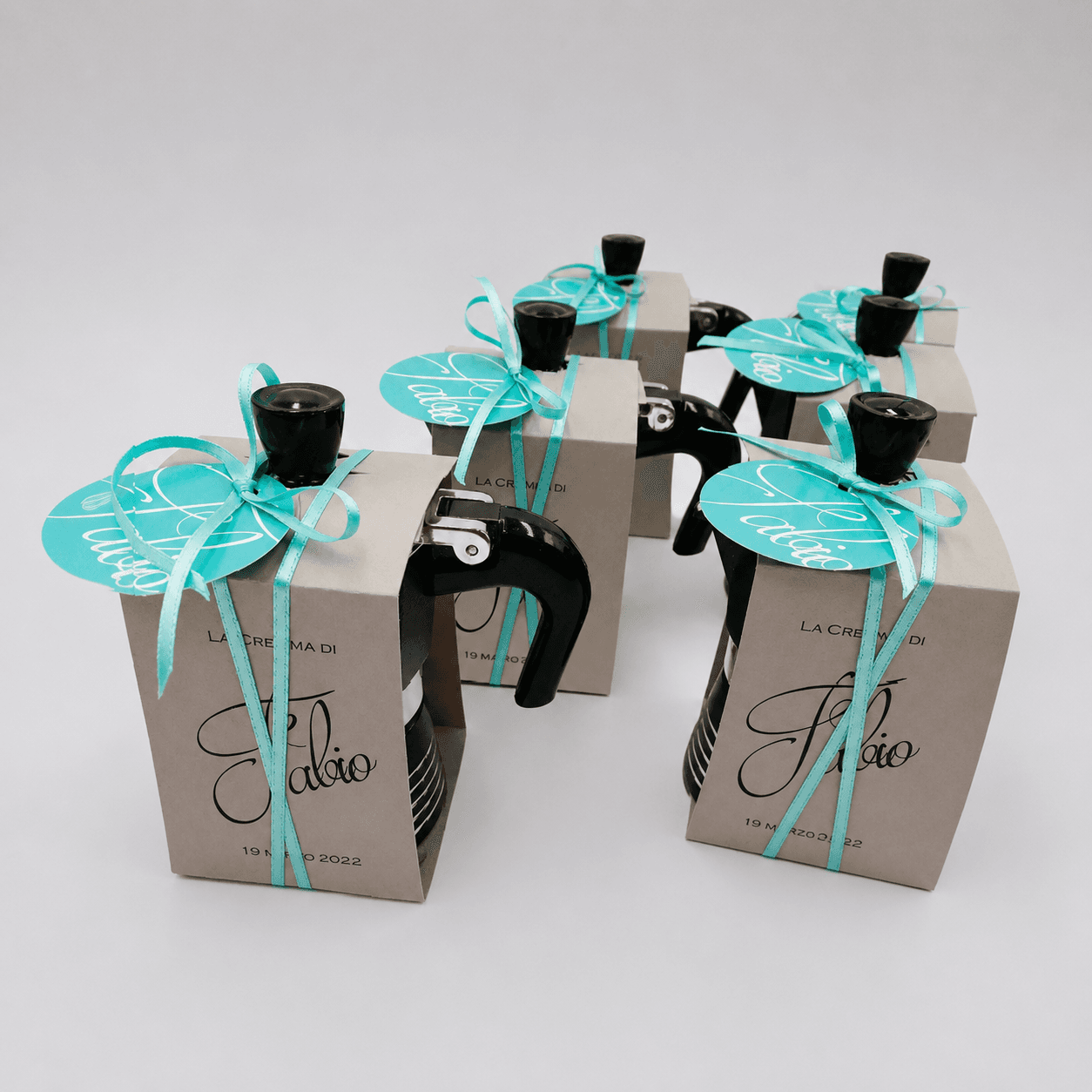 Scatole bomboniera personalizzate con boccetta d'olio e nastro turchese, esempio di packaging